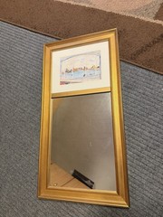 wall mirror with a gold-tone wood or composite frame, and a small paint